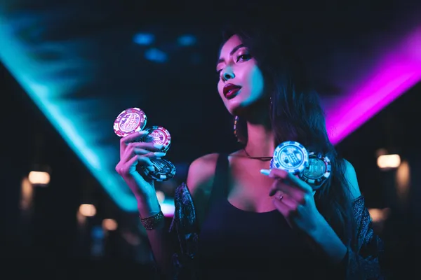 A young woman relaxing with her phone while dynamic casino elements float around her, illustrating the smooth mobile experience offered by the AMJILI app.