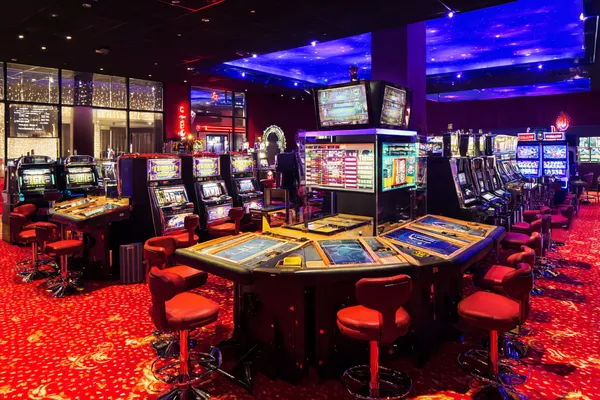 A stylish woman beside vibrant slot machines displaying glowing sevens, showcasing the variety of top slots at AMJILI.