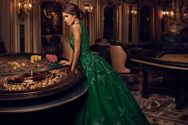 A woman in a luxurious green gown next to an ornate roulette wheel, capturing the upscale casino mood of AMJILI.