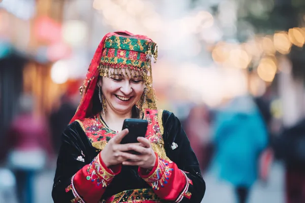 A player using their smartphone during a festive local event, representing AMJILI’s fully mobile-friendly casino.